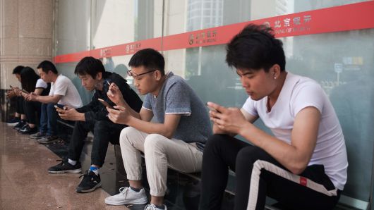 People use their mobile phones outside an office building in Beijing on May 24, 2018.? 